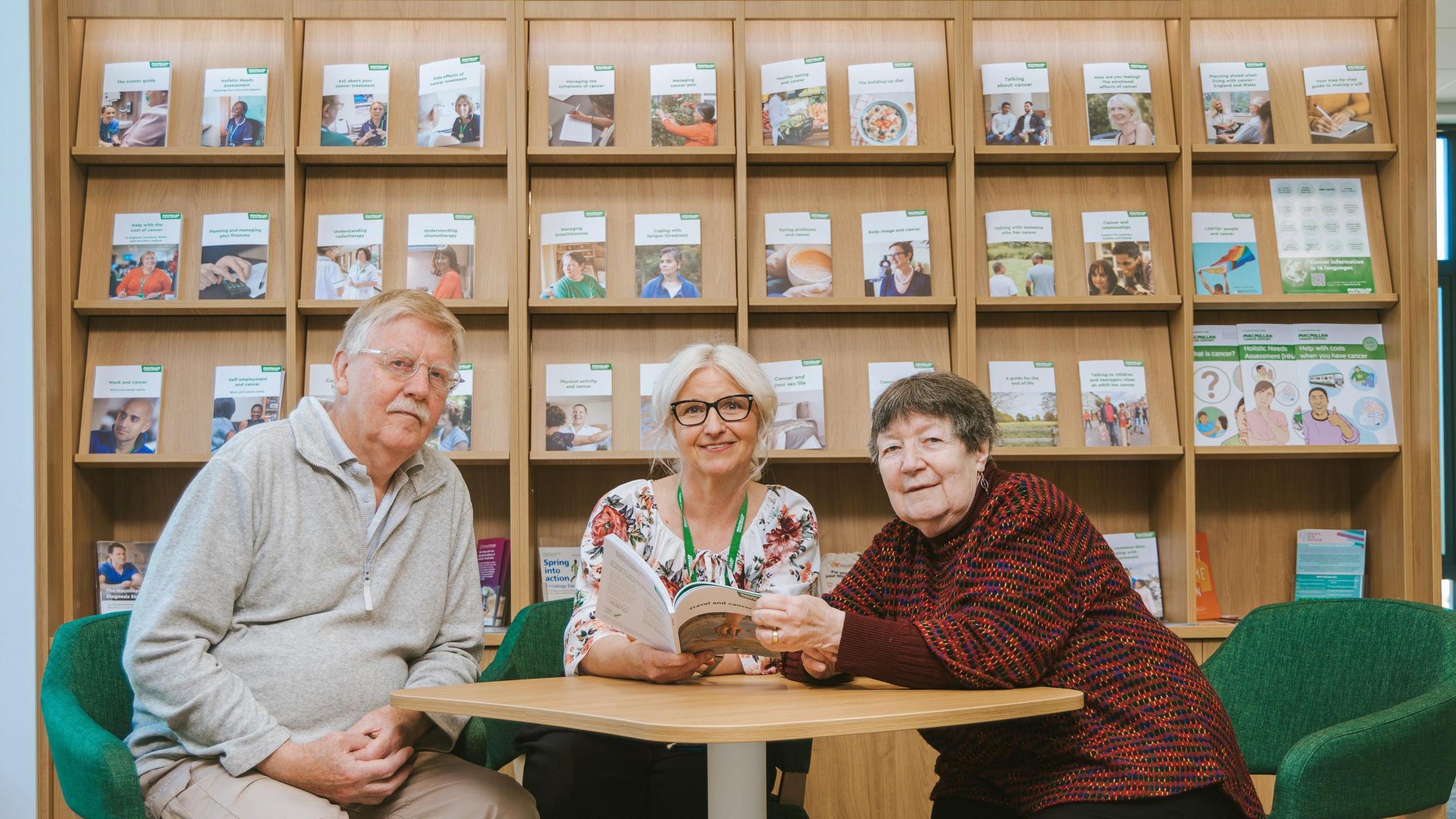 An image of three people sat around a table in front of a bookcase showcasing leaflets.