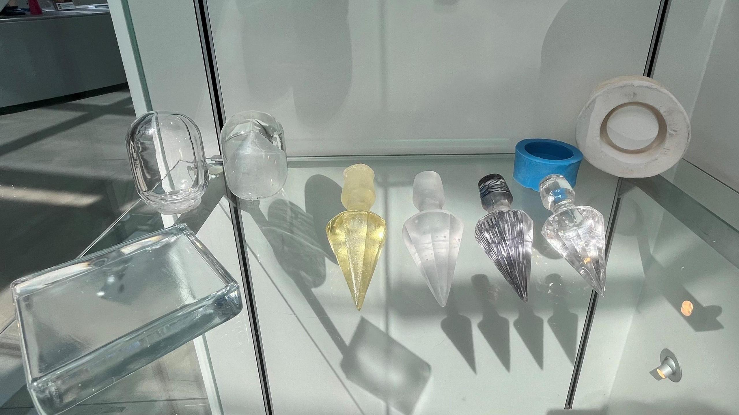 Sharp glass objects in intricate shapes are on display. The items are shiny and in different colours.