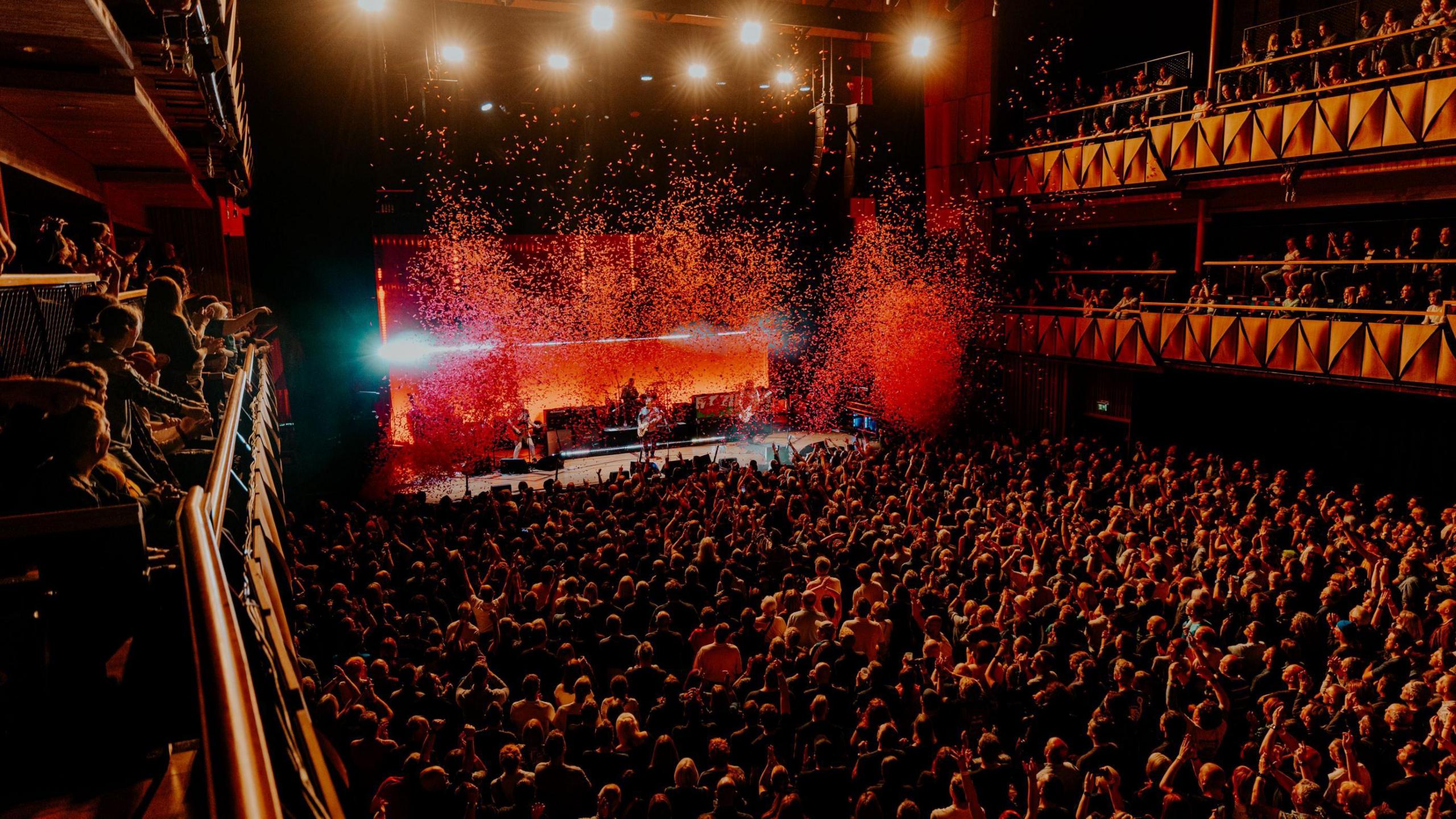 The main auditorium at the Bristol Beacon is seen full as the Manic Street Preachers play on stage. The image is taken from the back of the hall