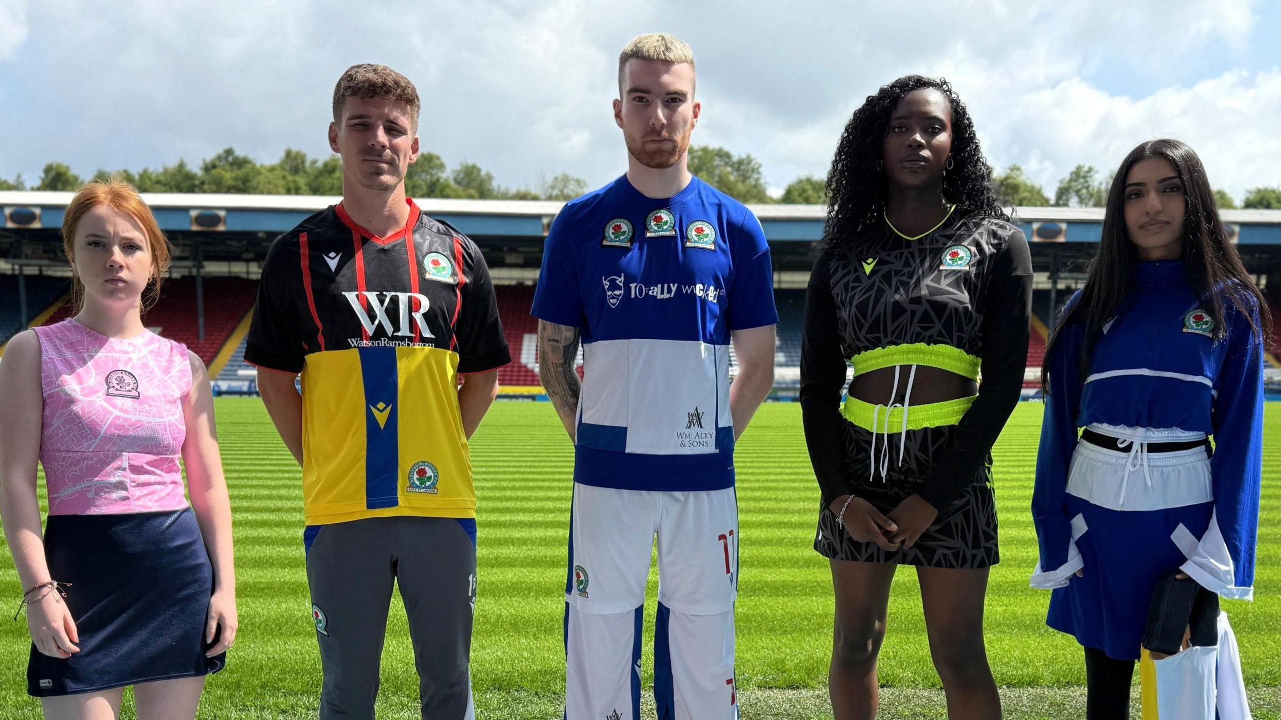Five models - three women and two men on Blackburn Rovers' pitch at Ewood Park wearing recycled football kits.
