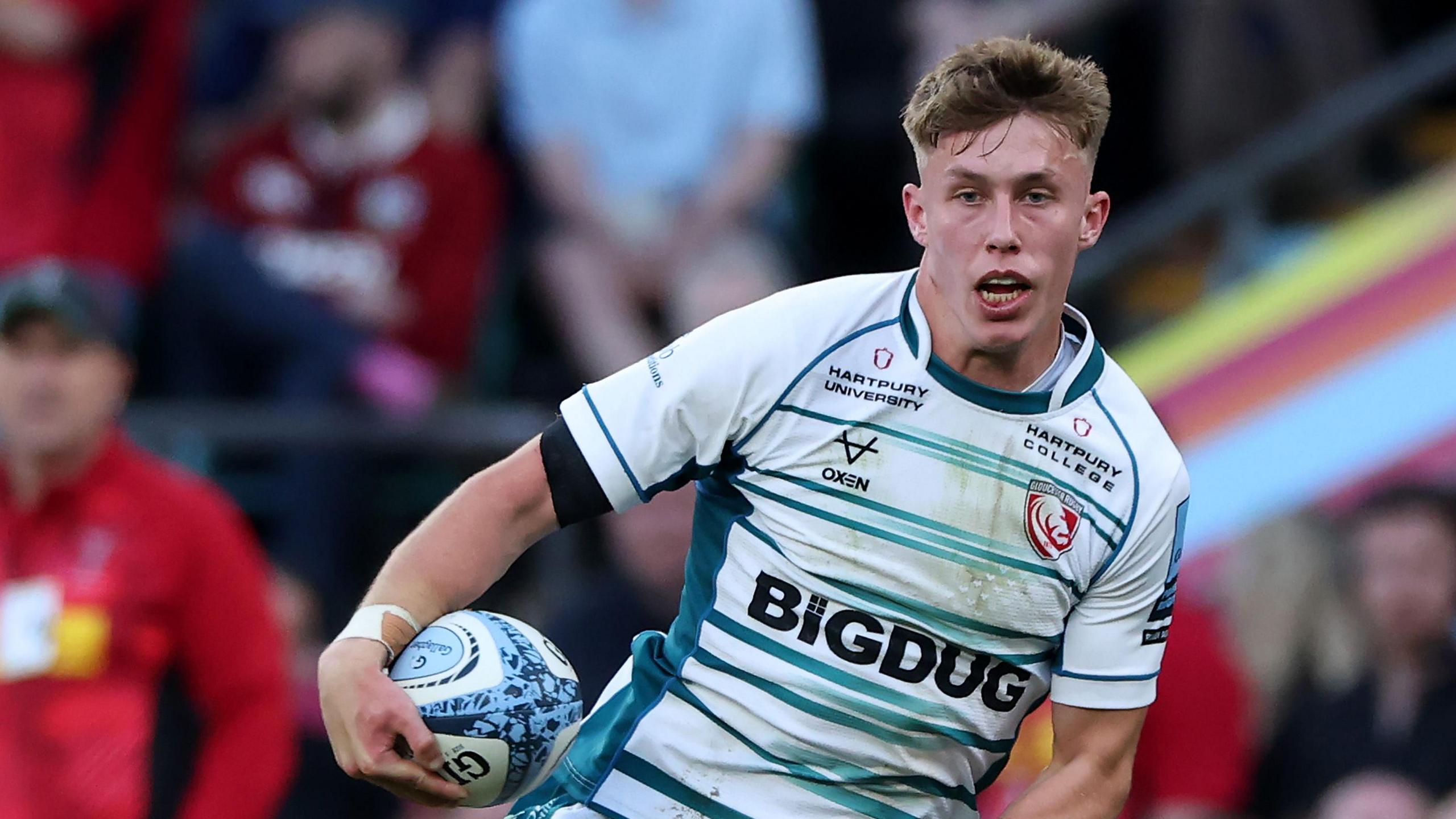 Jack Cotgreave runs with the ball under one arm while playing for Gloucester