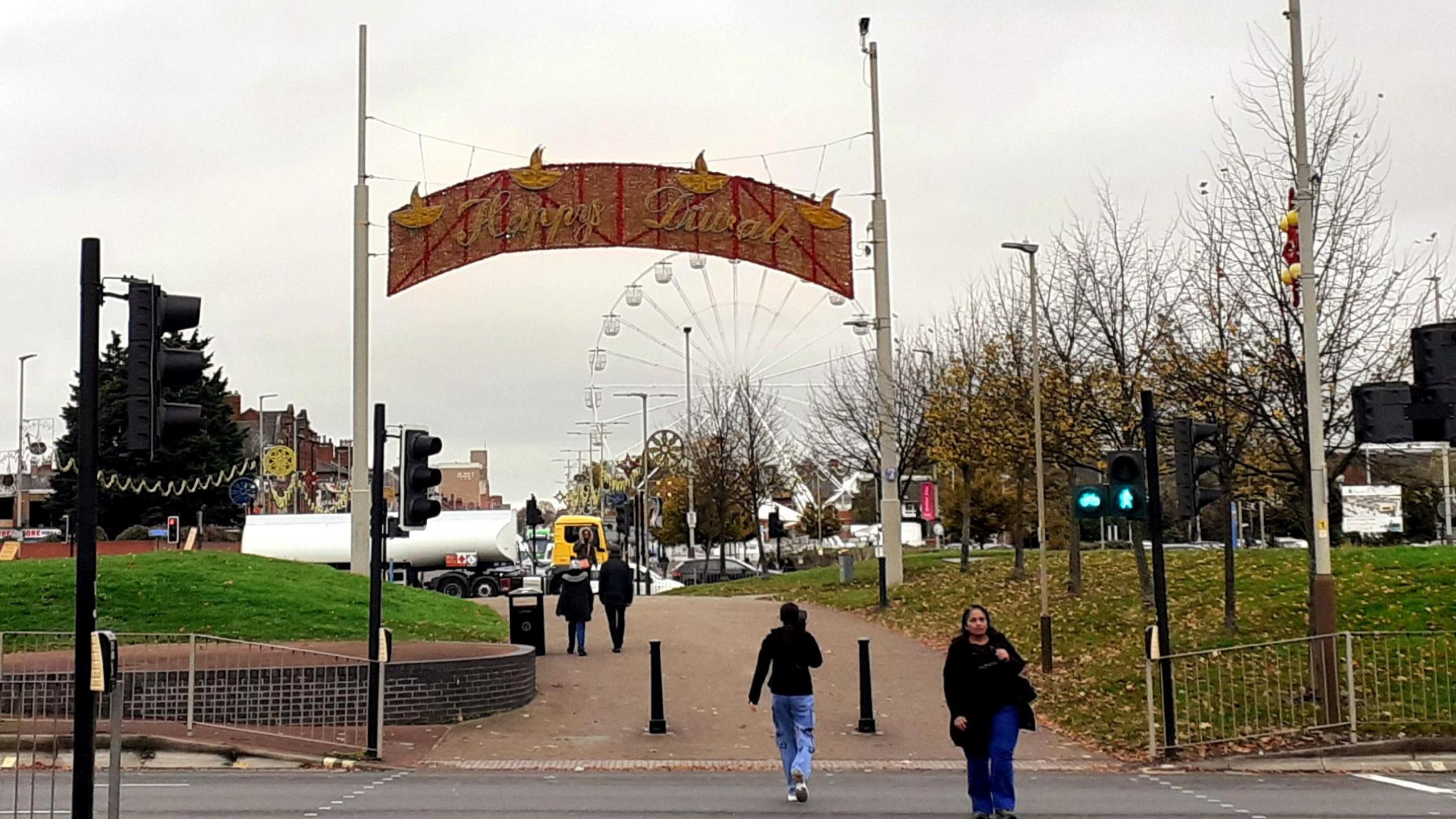 A large Happy Diwali sign over a footpath into Belgrave, with the Wheel of Light behind it