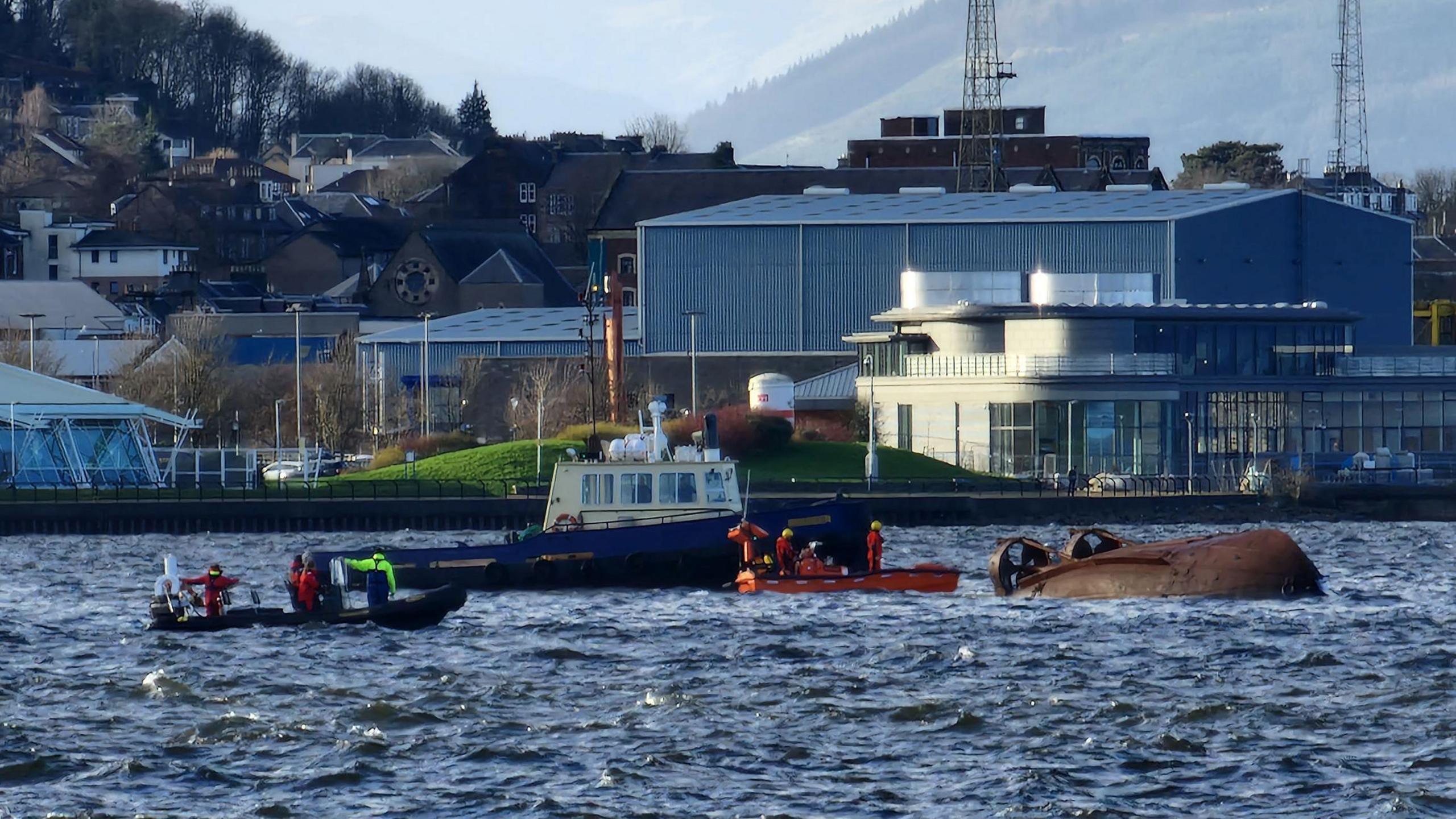 Salvage crews look for survivors after MV Biter capsized. Two boats are around the capsized vessel. 