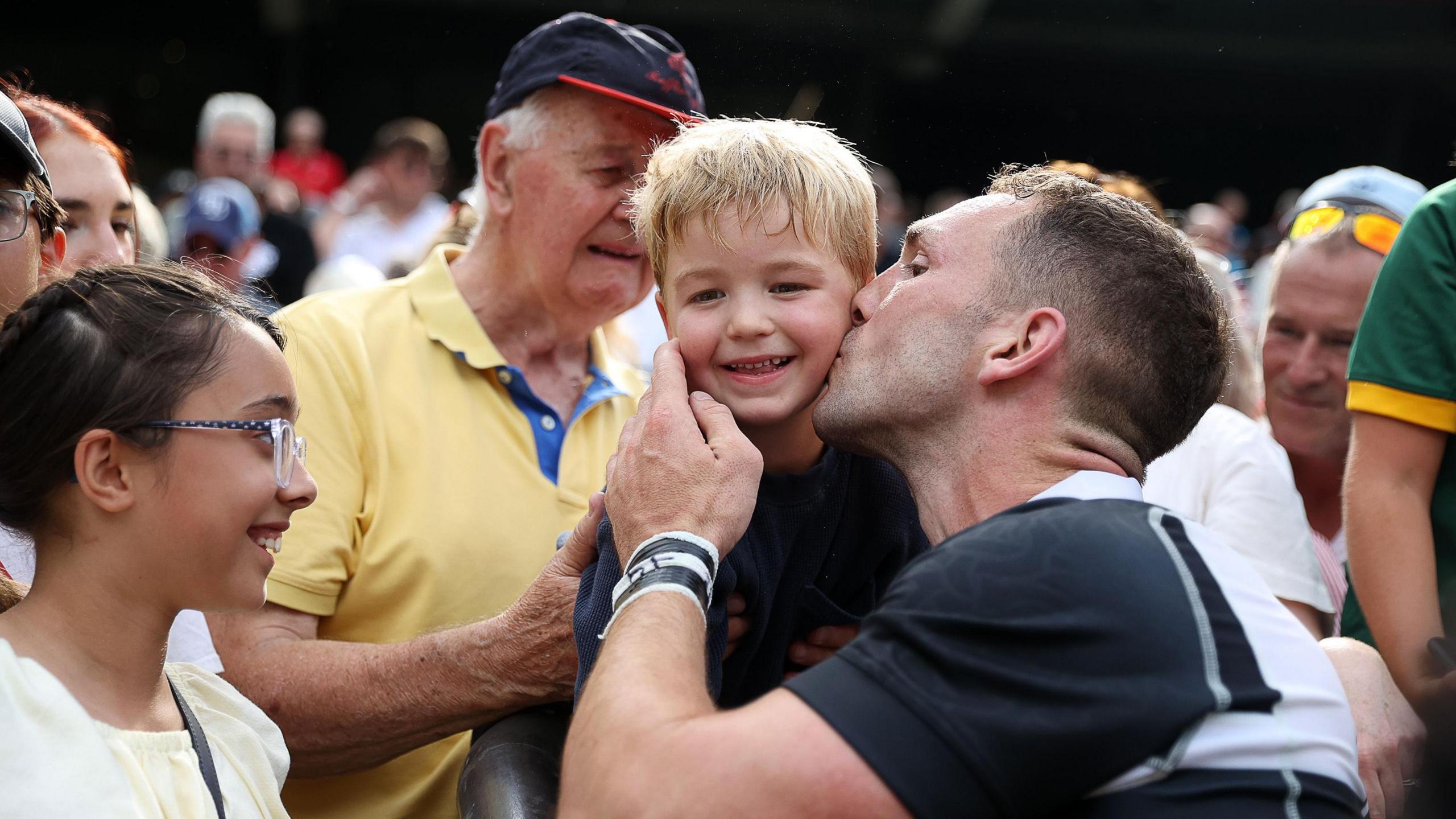 George North kisses his one of his two sons after the Barbarians game