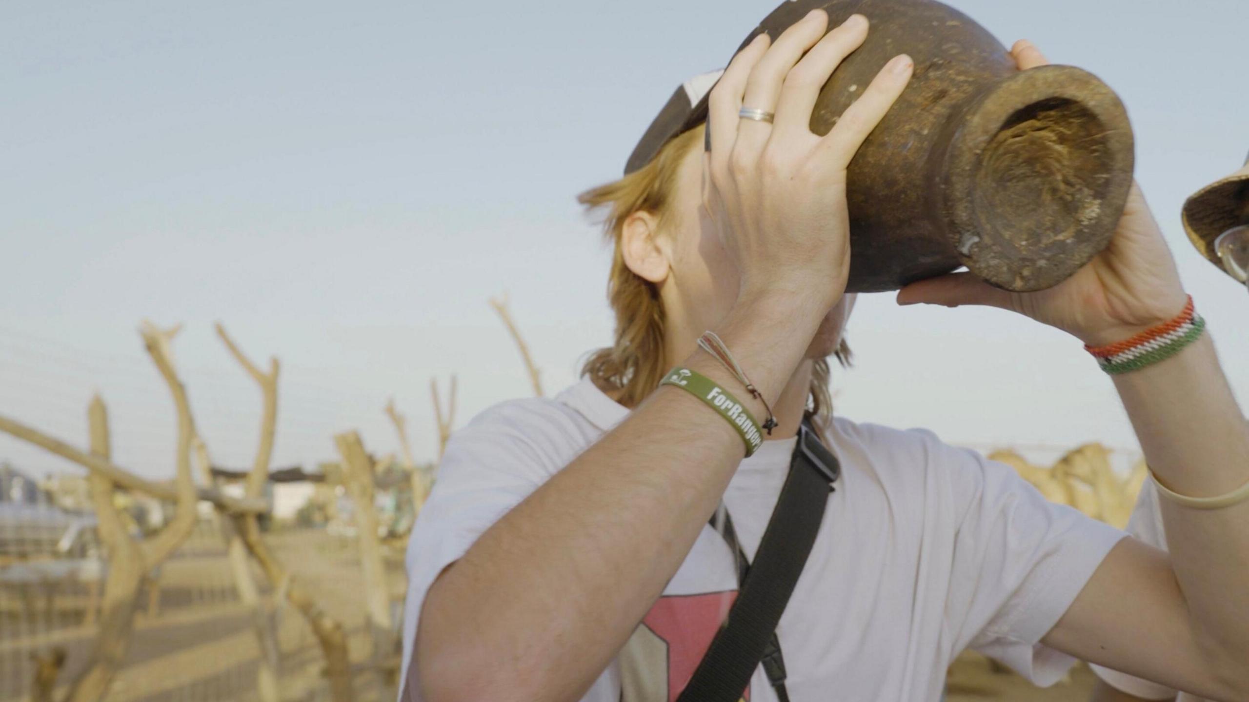 Henry Harte drinking camel’s milk from a wooden pail