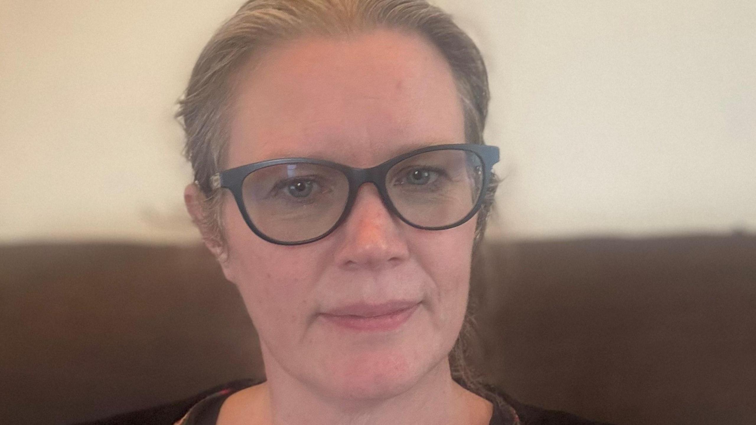 A woman with brownish hair pulled back off her face and glasses