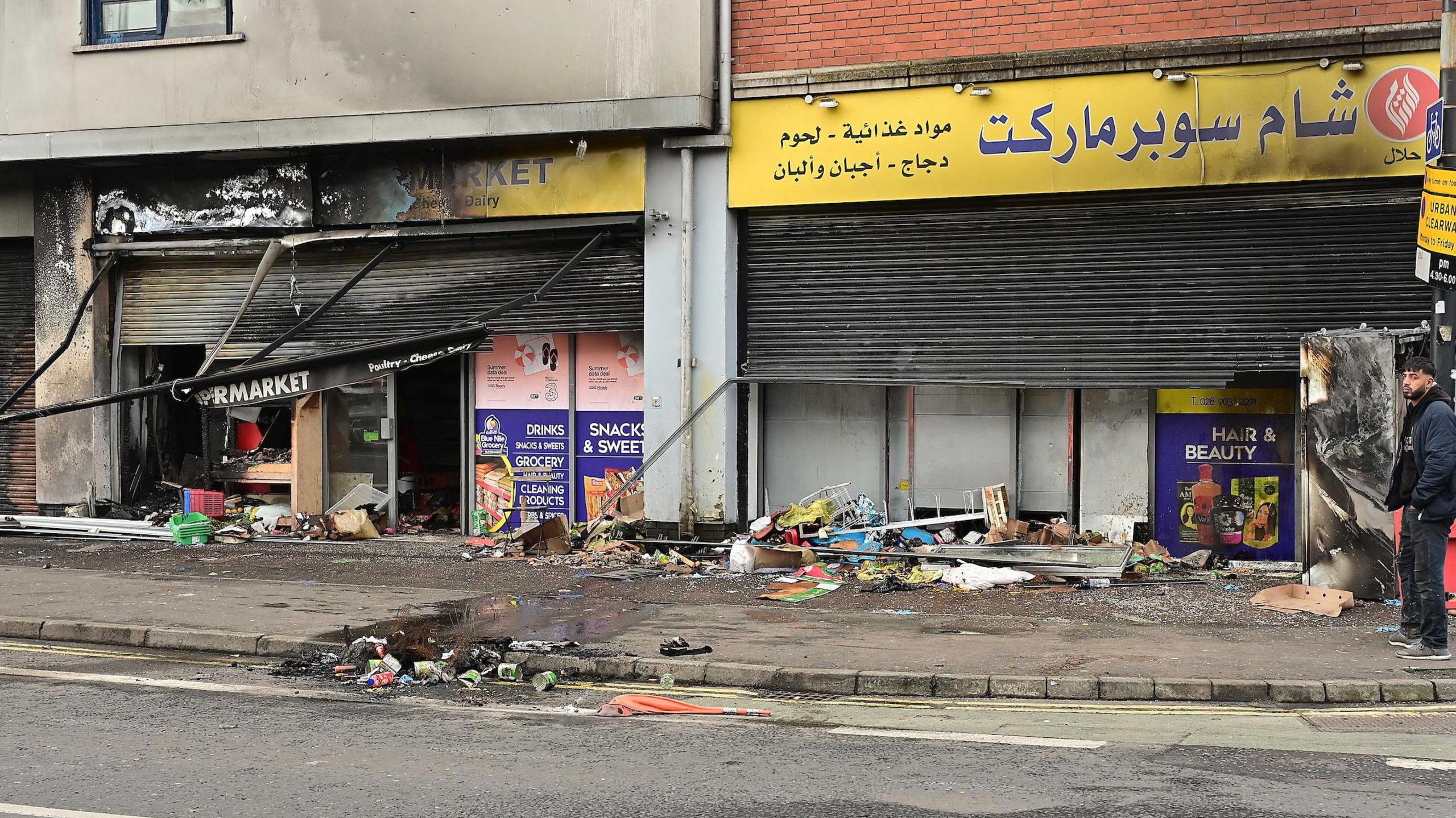 A burnt out supermarket in Belfast.
The windows are broken, the shutters blackened and produce strewn across the street.