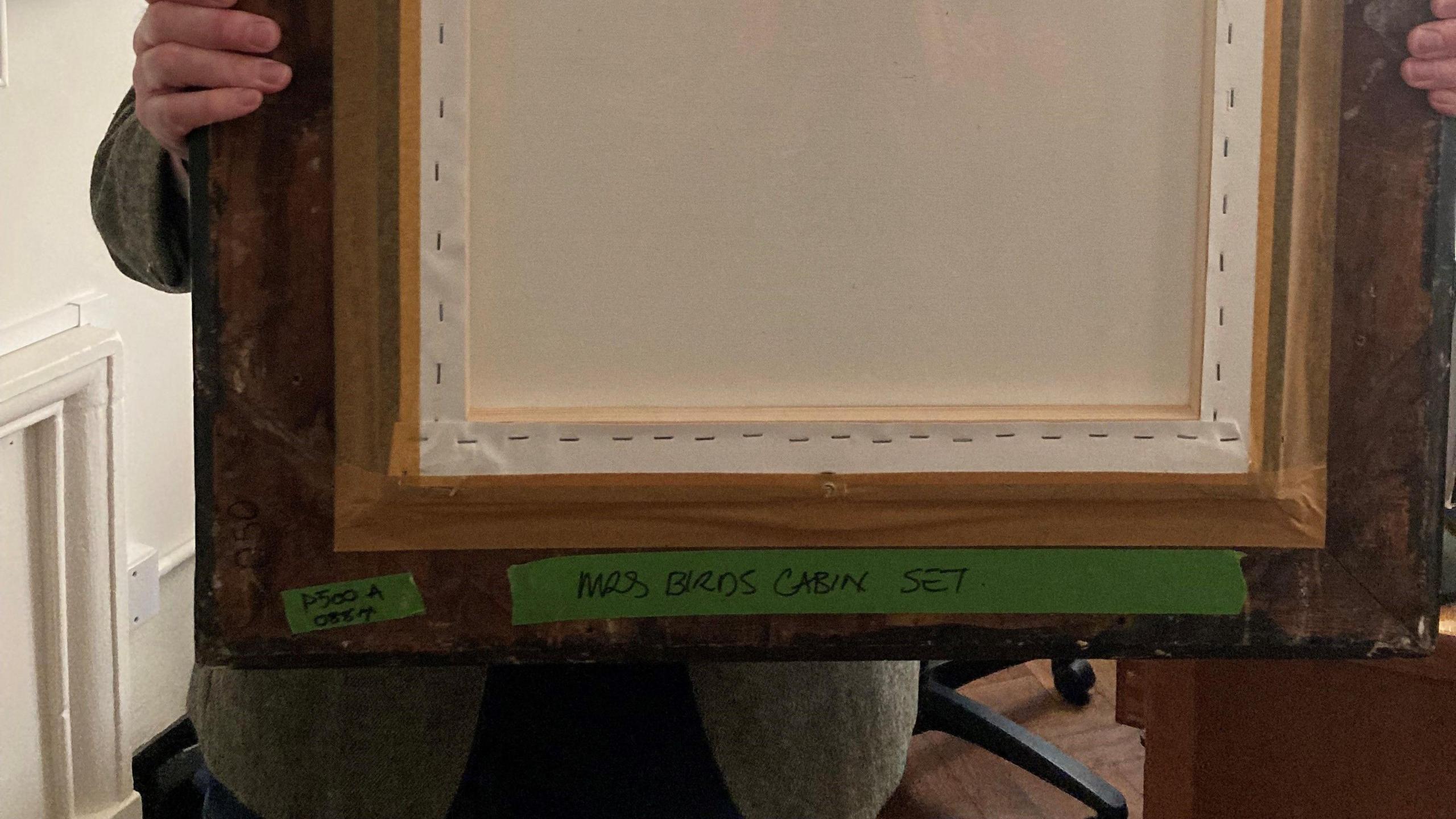 The pack of a painting with the words 'Mrs Brown Cabin set' written on green tape and stuck to the frame