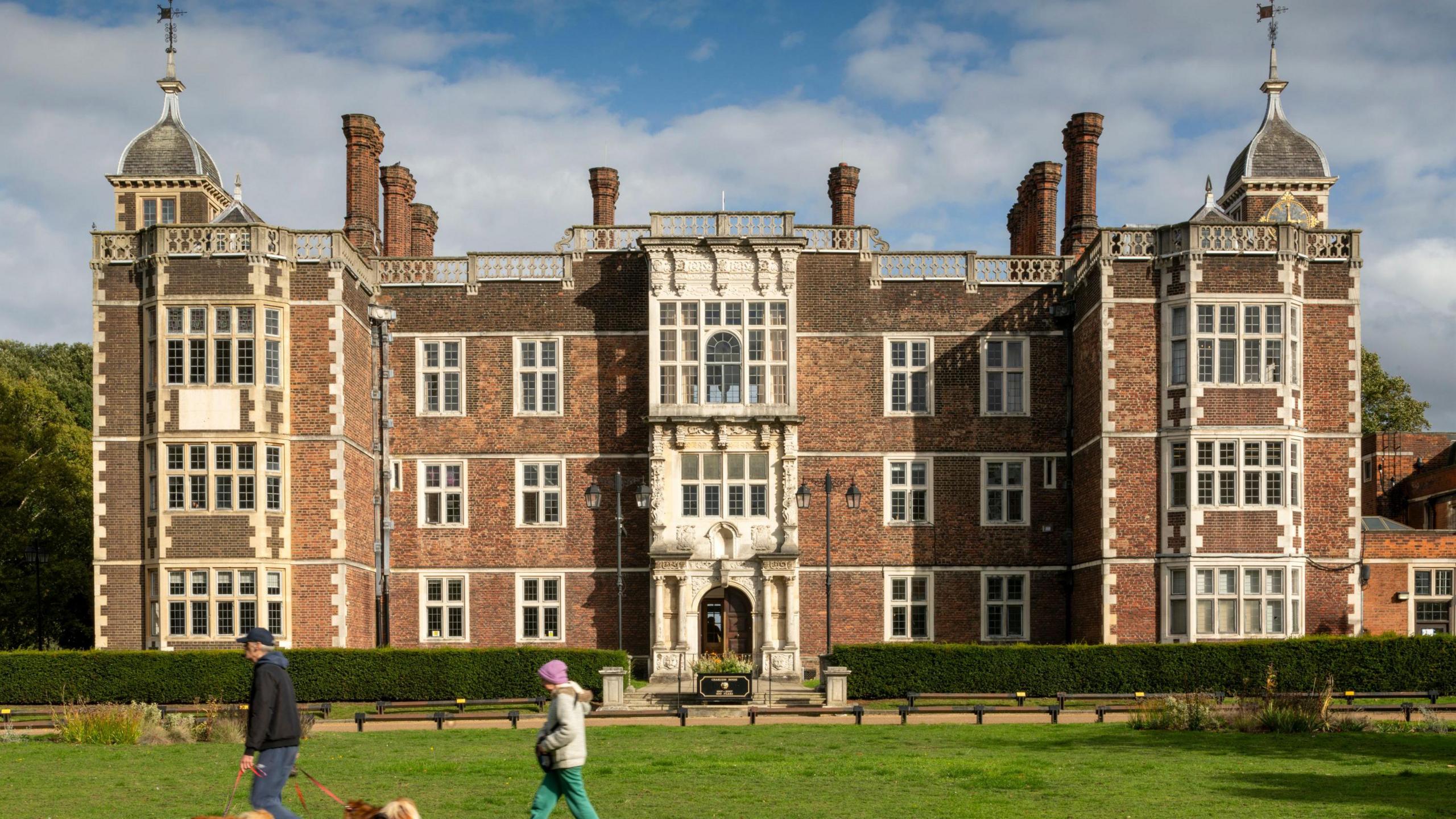 Charlton House on a sunny day with two dogwalkers in front of the building