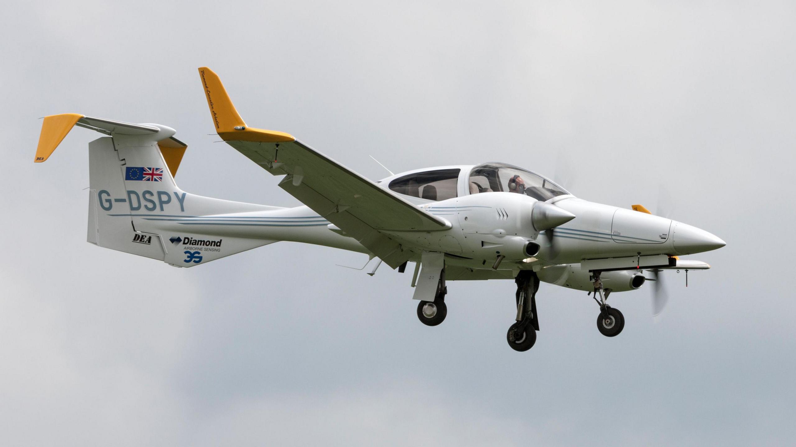 The Diamond DA42 MPP twin engine light aircraft G-DSPY on approach to land at Waddington. It is white with yellow wing tips.