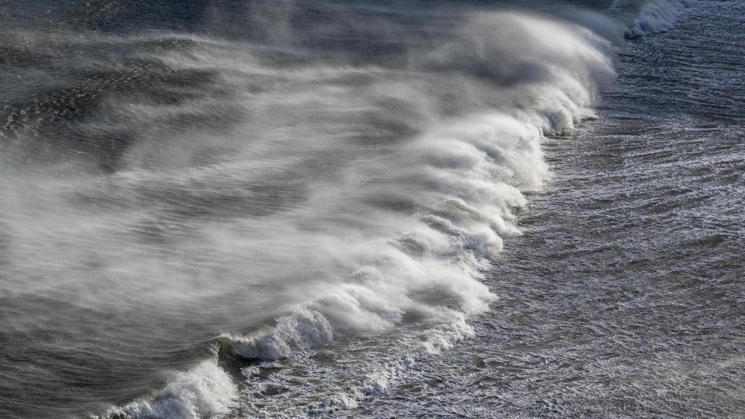 Overhead shot of ocean with large waves crashing on to water. The water is murky and ominous.