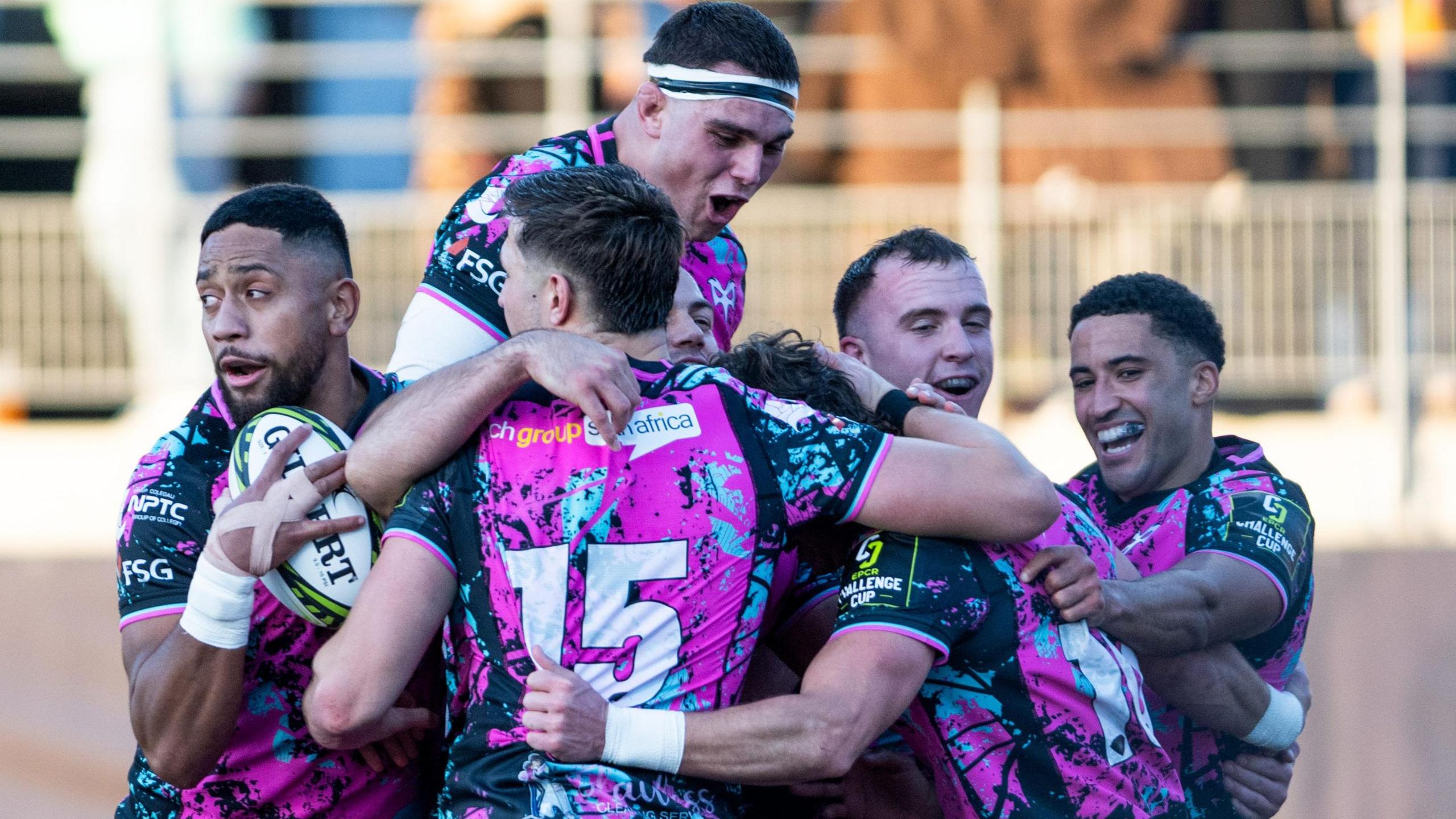 Six Ospreys players in a huddle celebrating scoring a try in their win at Montauban in the Challenge Cup