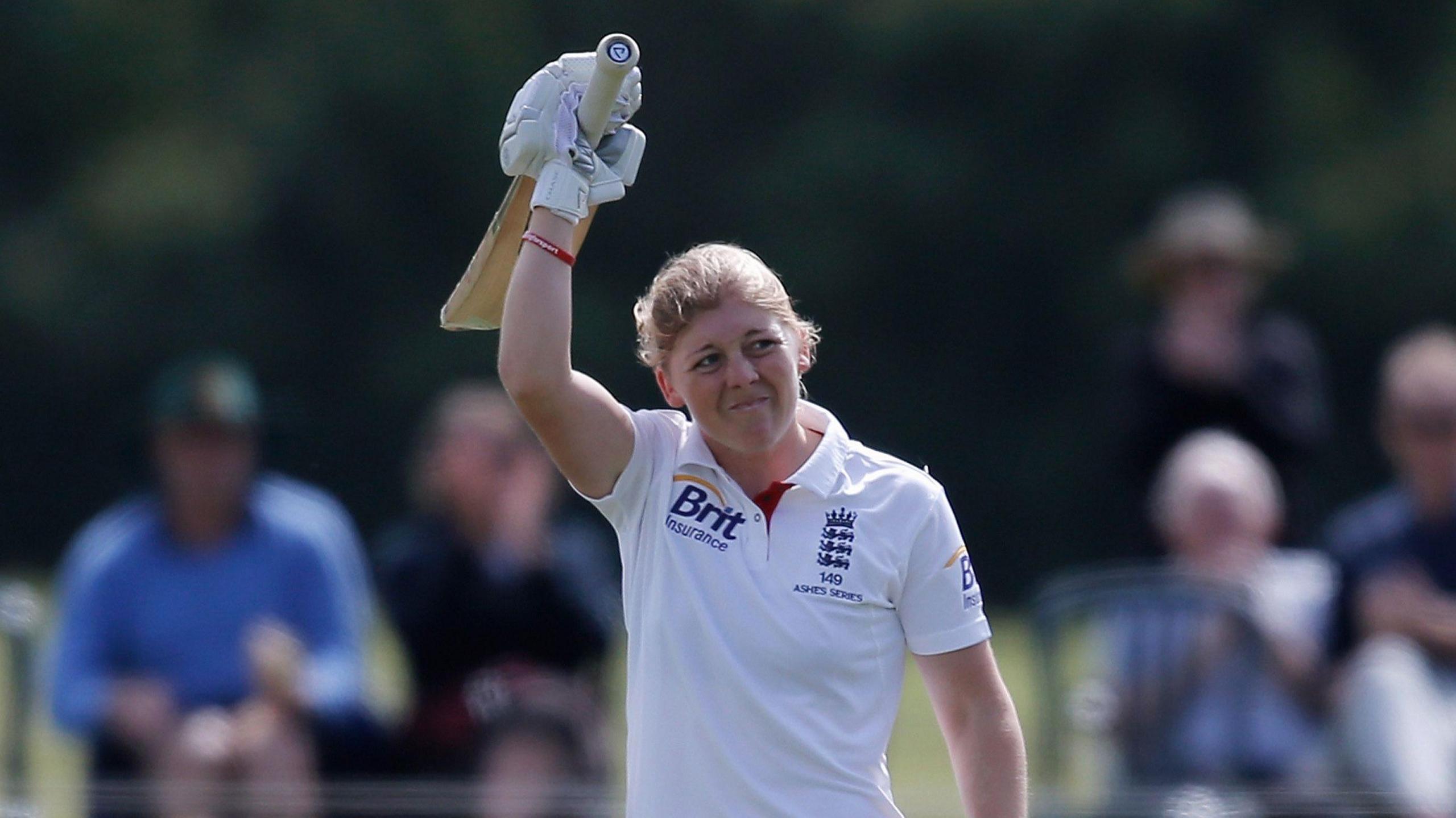 Heather Knight in whites raising her bat