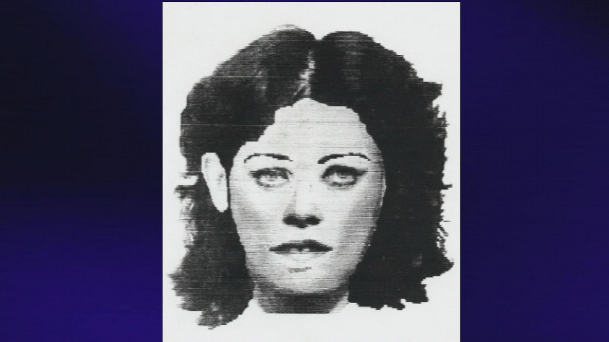 A black and white drawing of a woman with medium to long dark hair on a white page is placed against a blue background. The woman's hair is parted in the middle and her right ear is visible. She has thin, dark eyebrows and dark make up around her eyes. The drawing is cut off at the neckline and has no background.