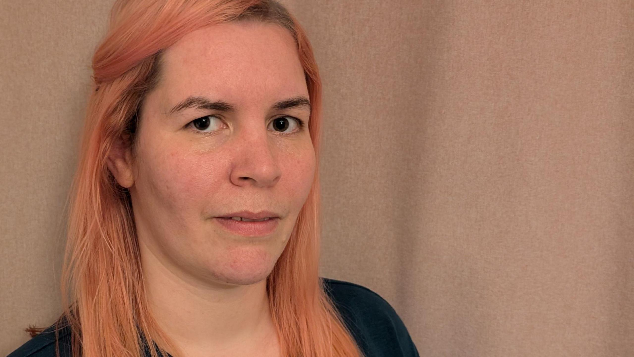 Woman in her thirties with long strawberry blonde hair and a pensive look on her face