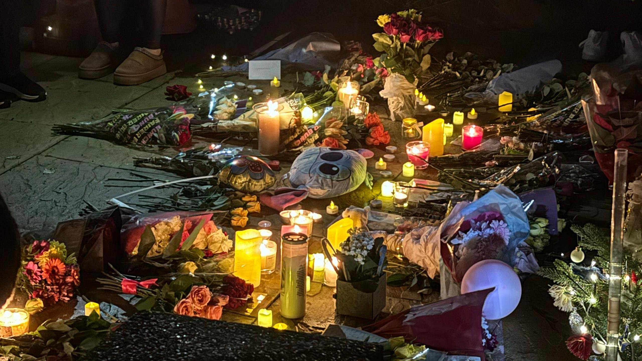 A tribute to Sara Sharif is seen with candles, balloons, flowers and a mini Christmas tree on the ground