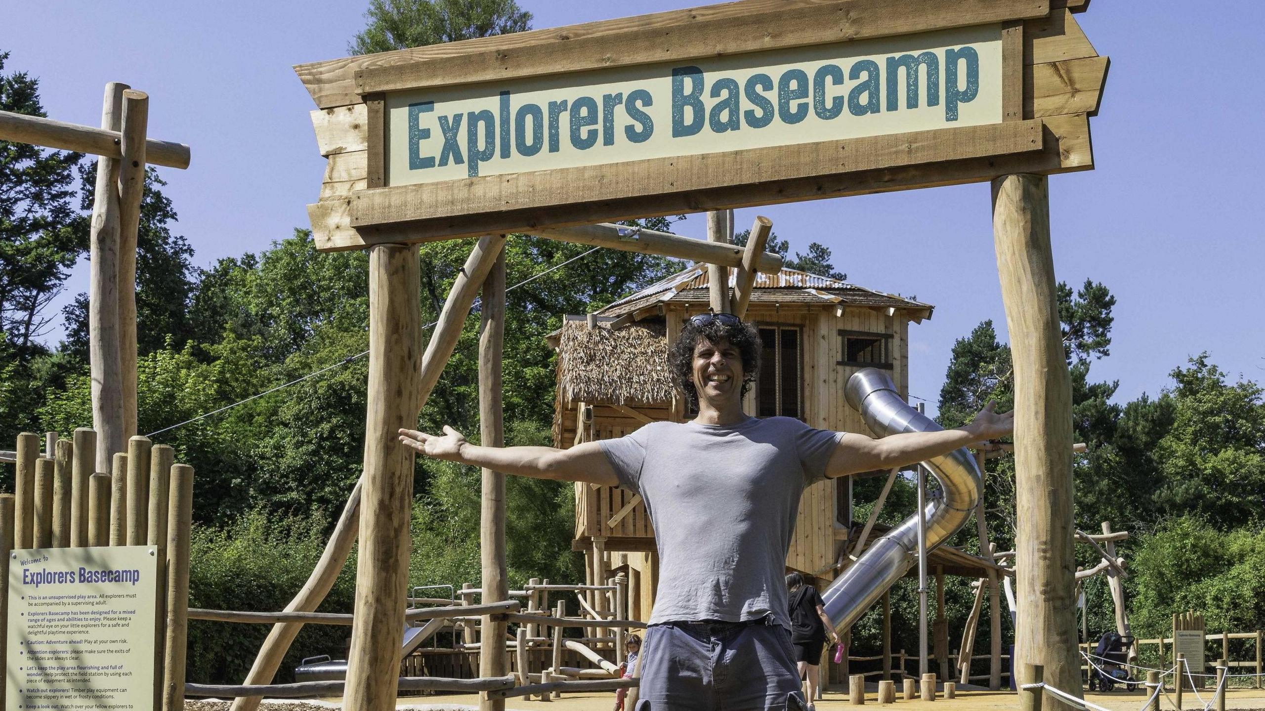 TV presenter Andy Day stands with his arms outstretched at the entrance of the new Explorers Basecamp play area at Bristol Zoo Project