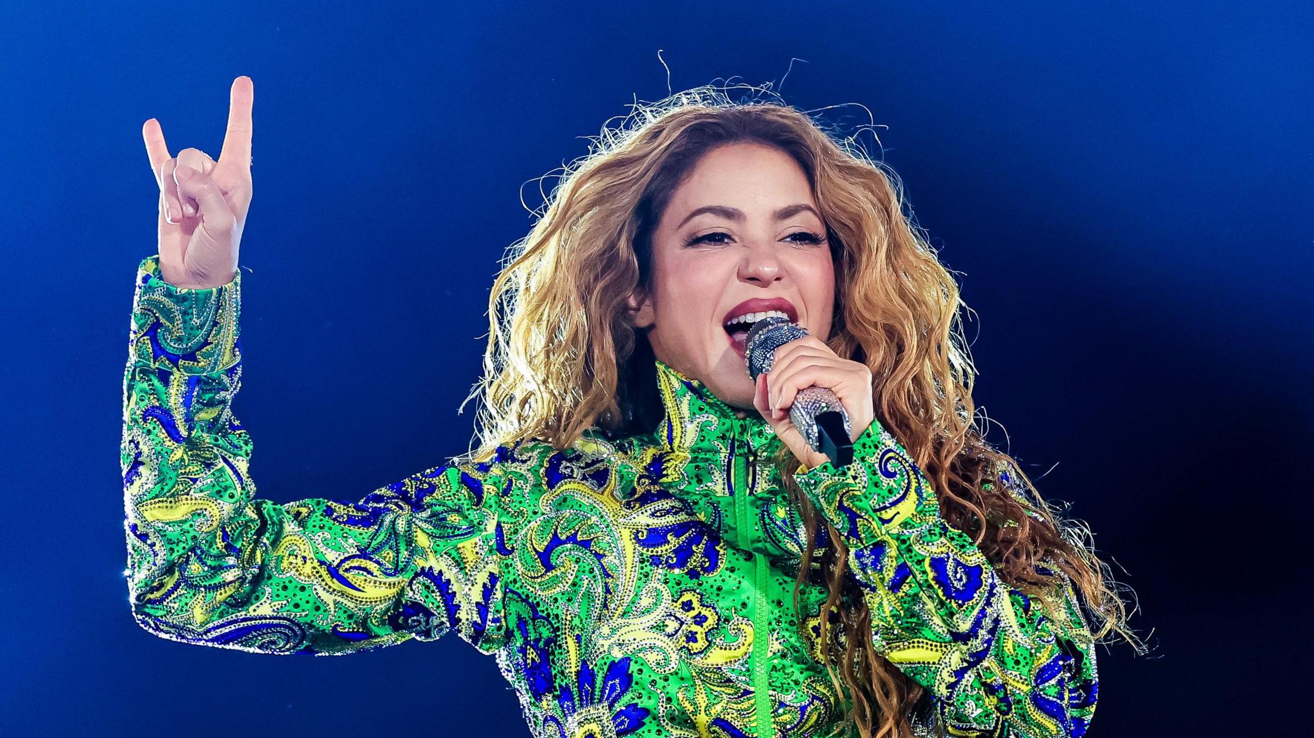 Singer Shakira performing in a green jacket.