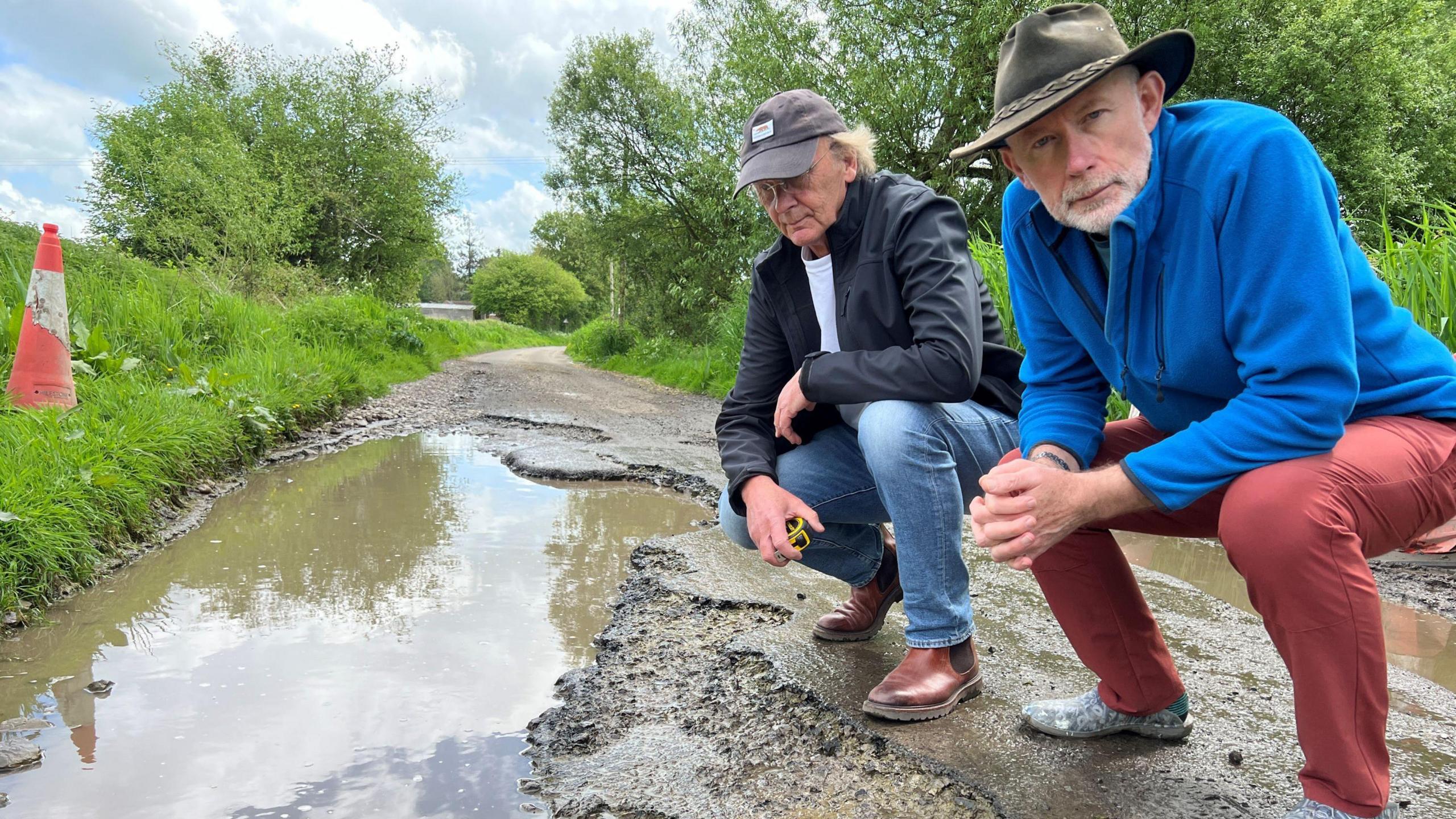 Vince Jenkins and David Bennett crouching next to the pothole