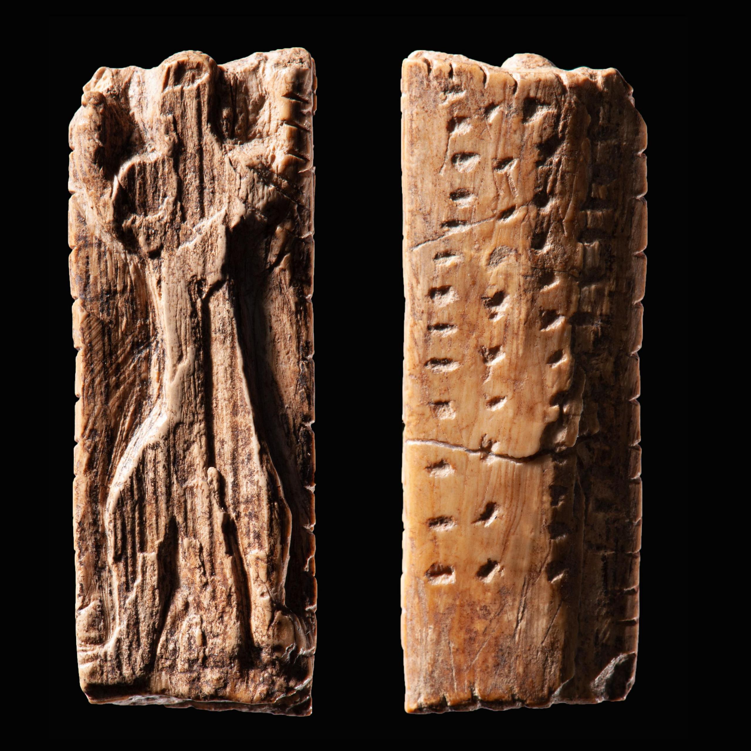 Small ivory plaque with an anthropomorphic figure and several rows of notches and dots. Front and back view of the same plaque.