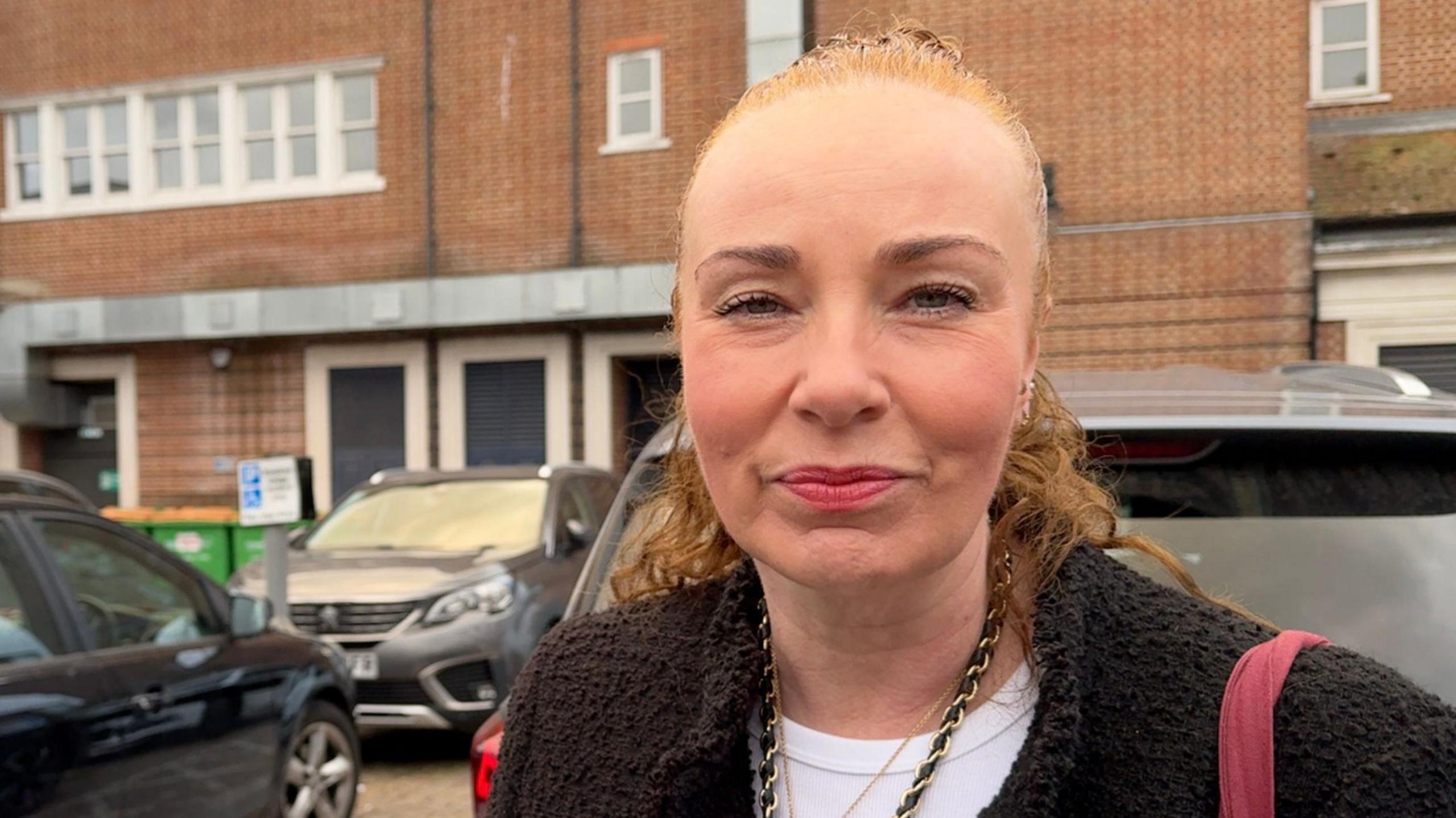 Woman standing in a car park.