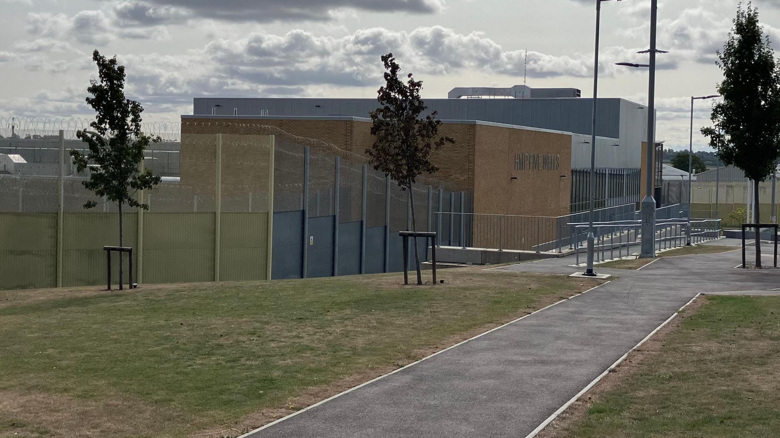 A long shot of the outside of the prison with high walls with barbed wire