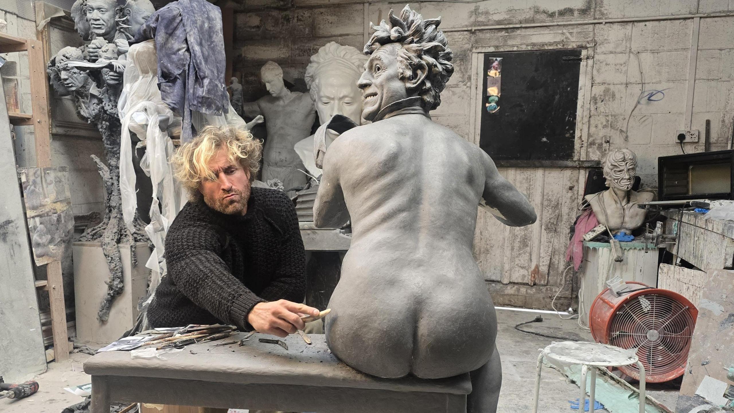 Llun y cerflun gyda'r cerflunydd Nick Elphick