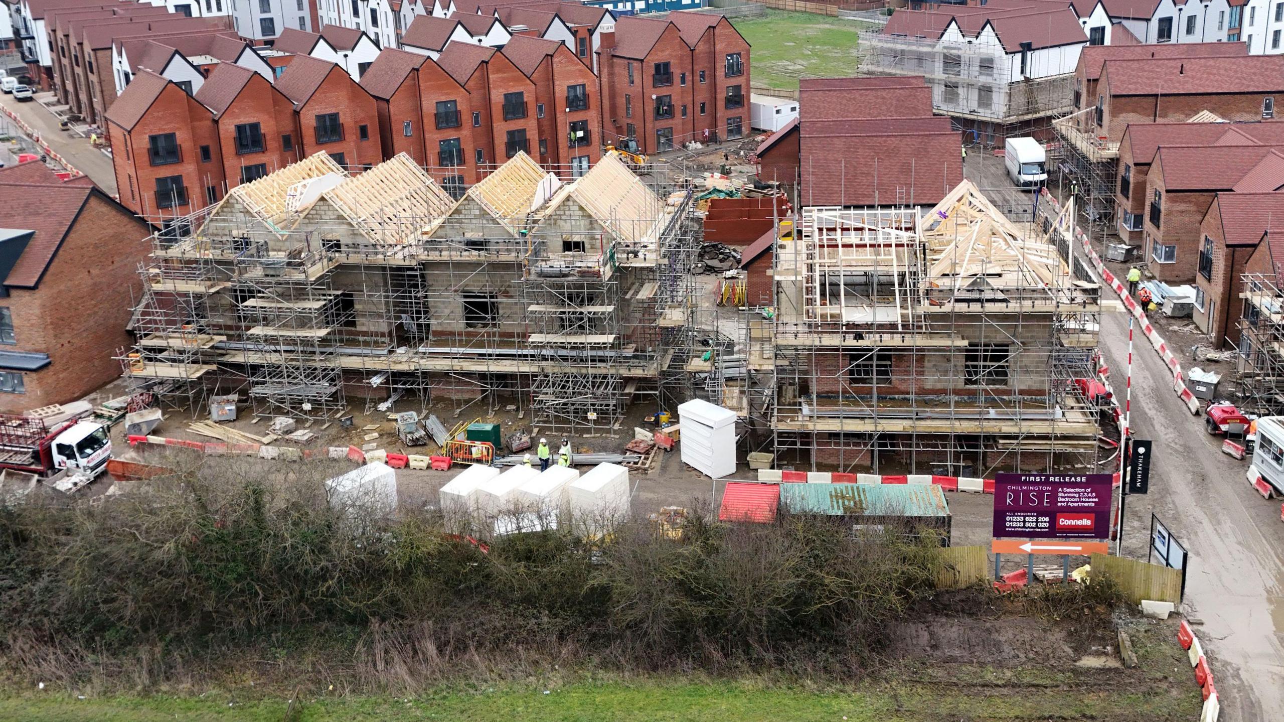 Construction work on part of the Chilmington Green housing development in Ashford, Kent. The picture shows half-built houses with scaffolding on, with completed three-storey buildings behind