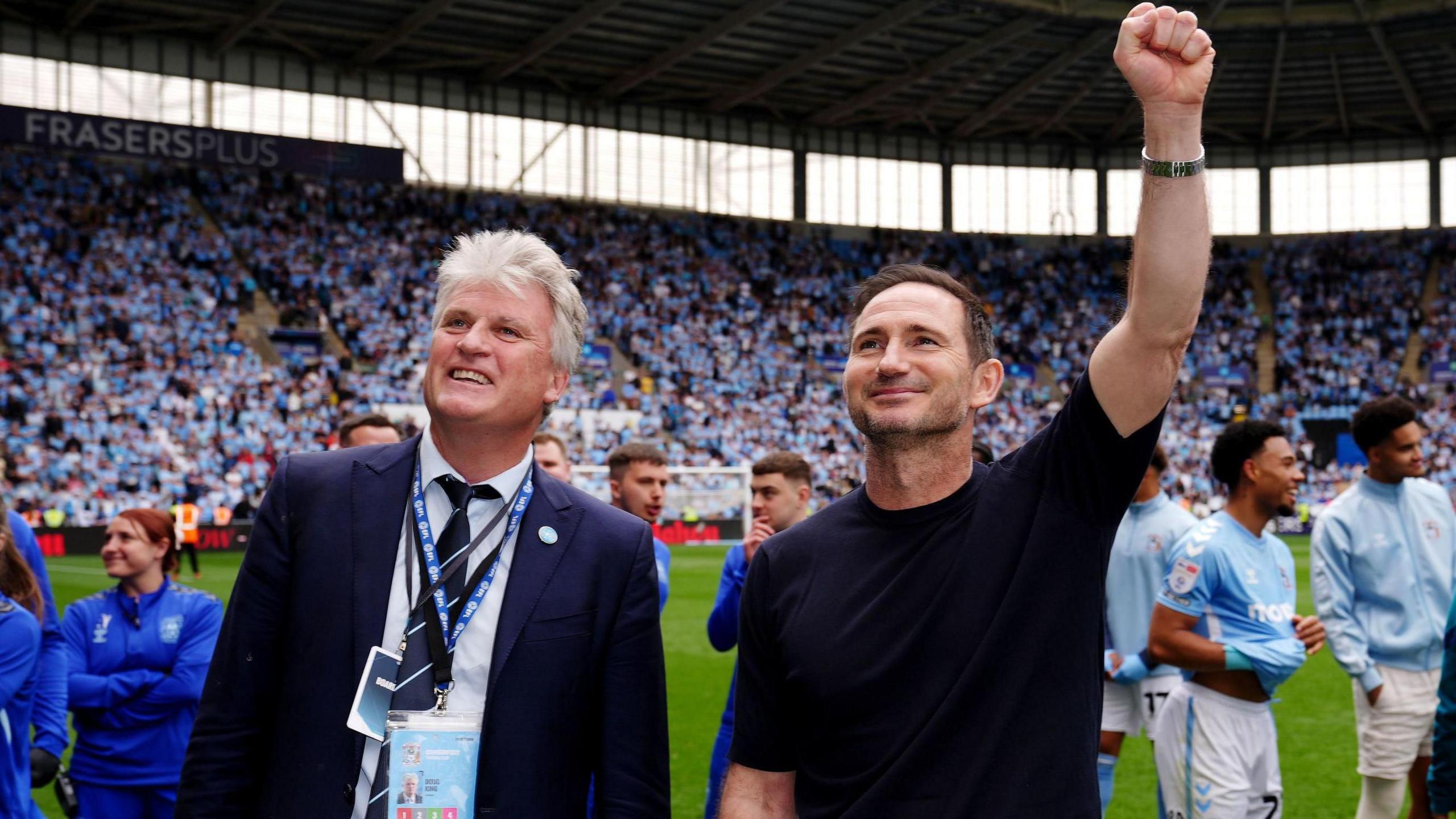 Coventry City owner Doug King pictured with manager Frank Lampard at the Coventry Building Society Arena celebrating with fans. They are both smiling and Frank Lampard has his left first raised in celebration.