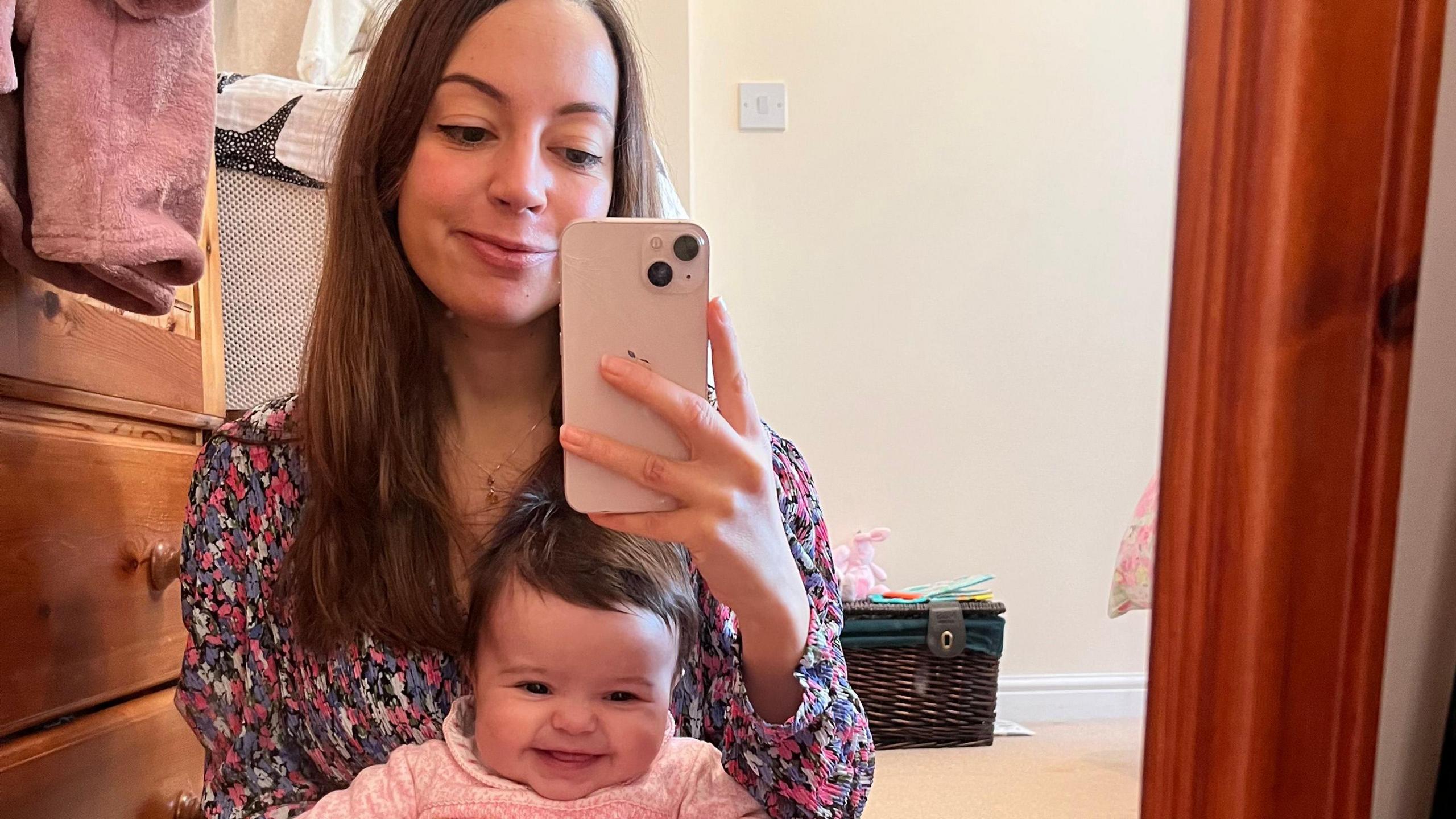 Rebecca sitting with her daughter in home. They are both smiling and seeing on the floor.