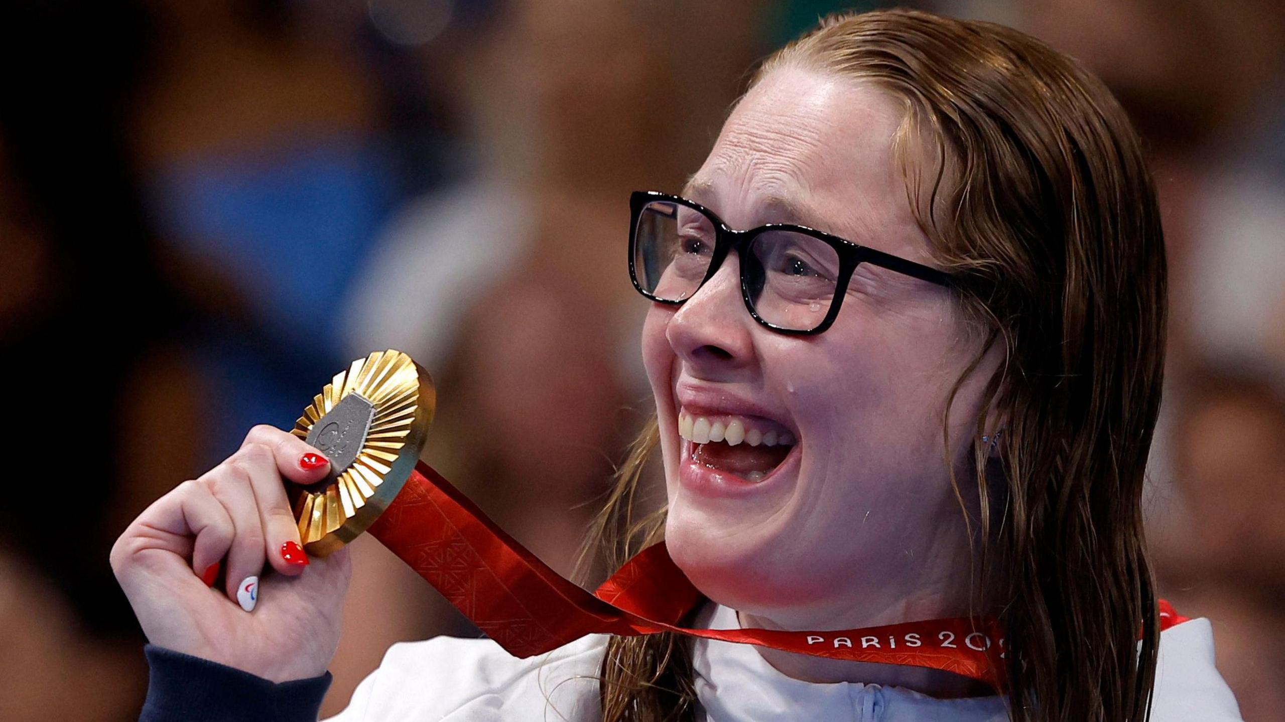 A tear rolls down Brock Whiston's face as she holds up her Paralympic gold medal