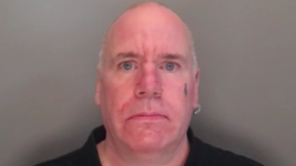 Mugshot of Crozier. He is bald and clean shaven with a black tattoo on his cheek.