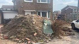 Huge pile of rubbish, rubble and earth on the drive of a two-storey new house