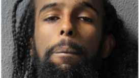 A police mugshot of Elyas Moussa, who has long dark dreadlocks and a beard