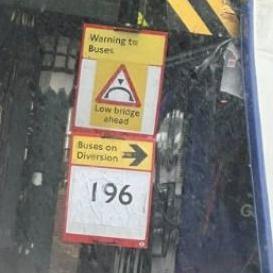 A blurred image of a warning sign, saying buses are too tall for the bridge