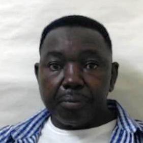 A mugshot of Walter Masocha. He is looking striaght at the camera. He is wearing a blue and white checked shirt over a white T-shirt.