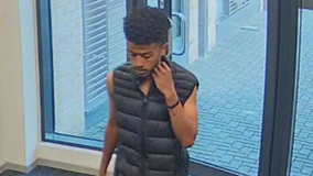 A man in a black vest captured by CCTV in a building. He is looking down.