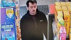 CCTV image of a man with dark hair, a moustache and goatee