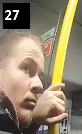 A bearded man standing on a bus or train