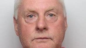 A close crop of a mugshot of Paul Richardson. He is in his sixties and has a pink face, white hair, and watery blue eyes.