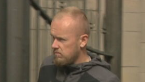 Ross Wallace leaves Edinburgh Sherriff Court. He has fair short hair and a trimmed fair beard. He wears a dark jacket.
