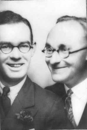 Gareth Jones (left) and Reinhard Haferkorn (right) posing in a photo booth. Both are wearing dark suits, collar and tie and both wearing round glasses. It is a black and white image.