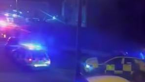A grab from a video showing emergency services with blue lights in dark at scene of fire.