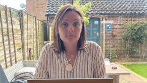 Sarah Wells sitting in front of her laptop at her home in Surrey