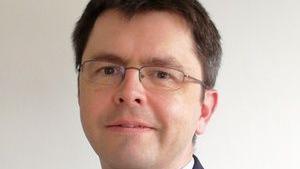 Headshot of David Hill. He has short brown hair and is wearing glasses, looking into the camera.