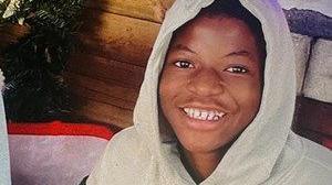 A boy wearing a grey hoodie while smiling at the camera.