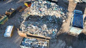 An aerial shot showing a large pile of mixed waste, with skips off to the left side and a vehicle to the right