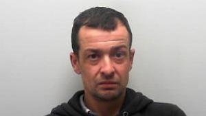 Custody picture of a man with short dark hair in a black hoodie.