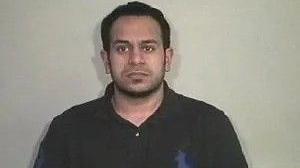 An old police mugshot of Yasar Hussain, wearing a black polo shirt