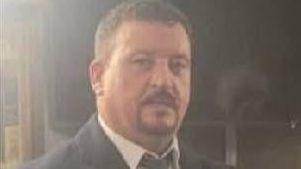 Young John Mongan is dressed in a black suit and tie and is wearing a white shirt